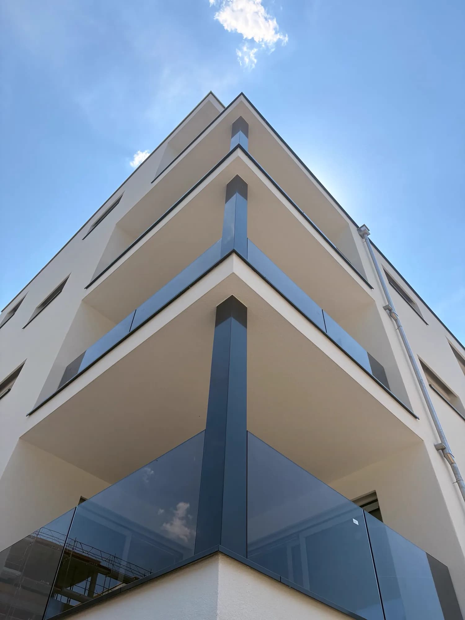 Ecke eines Neubaus, drei Geschosse mit Geländern aus Rauchglas, Arbeiten abgeschlossen